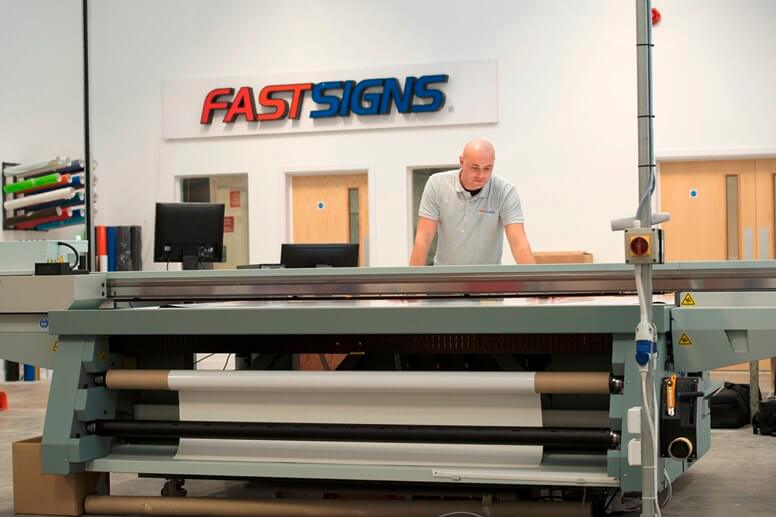 Fastsign employee working on printing machine