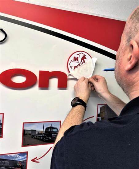 man installing wall graphic